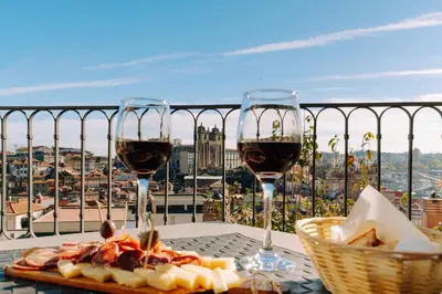 two glasses of wine and a plate of food on a table at Casa Dos Caldeireiros in Porto