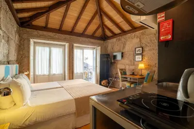 a bedroom with a bed and a kitchen with a stove at Casa Dos Caldeireiros in Porto