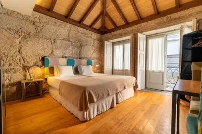 a bedroom with a bed and a stone wall at Casa Dos Caldeireiros in Porto