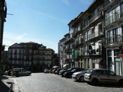 a street with cars parked on a cobblestone street at Porto Downtown Taipas in Porto