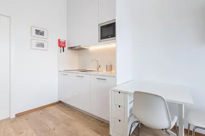 a white kitchen with a desk and a chair at GuestReady - Port Studio 2 in Vila Nova de Gaia