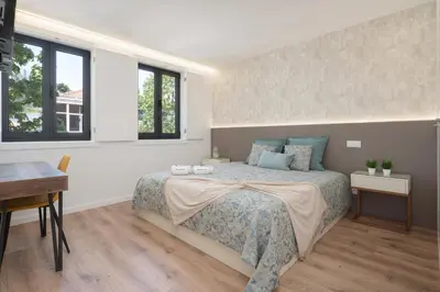 a bedroom with a bed and a desk and windows at Host Wise - Bright & Contemporary Flat - Ace Location in Porto