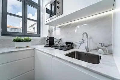 a white kitchen with a sink and a window at Nomad's Formosa - Apartments Porto in Porto