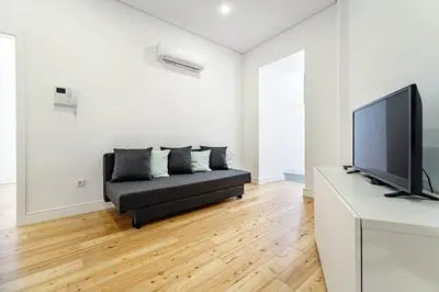 a living room with a black couch and a flat screen tv at Nomad's Formosa - Apartments Porto in Porto