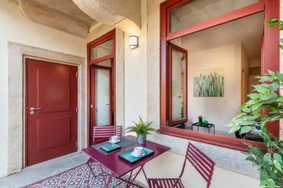 a patio with a red door and a table and chairs at Josephine Apartments in Porto
