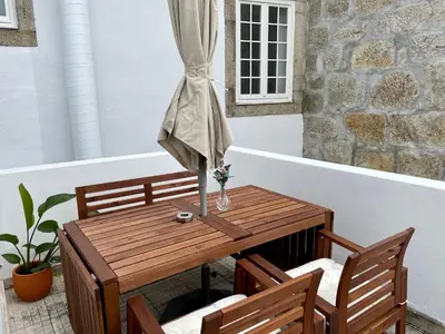 a wooden table with two chairs and an umbrella at Ribeira Cozy Apartment in Porto