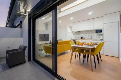 a dining room and kitchen with a table and yellow chairs at WHome Riverside View Premium Apartment w/ AC & Terrace in Porto