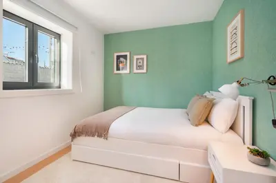 a bedroom with a white bed and a green wall at WHome Riverside View Premium Apartment w/ AC & Terrace in Porto