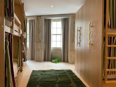 a room with a large window and a green rug at Lost Inn Porto Hostel in Porto