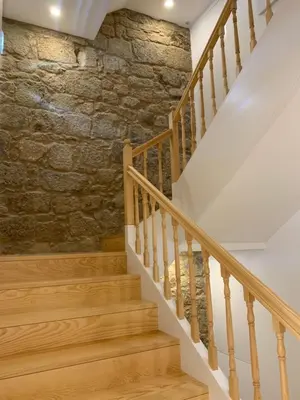 a staircase with wooden railings and a stone wall at Lost Inn Porto Hostel in Porto