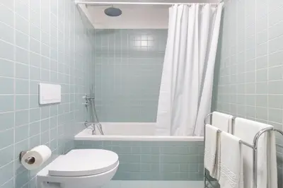 a blue tiled bathroom with a toilet and a tub at B Porto Casa da Música in Porto