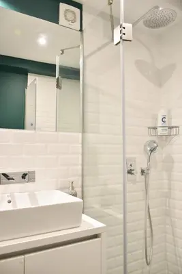 a white bathroom with a shower and a sink at Lindo apartamento 2 quartos com pátio - Batalha - APT C in Porto