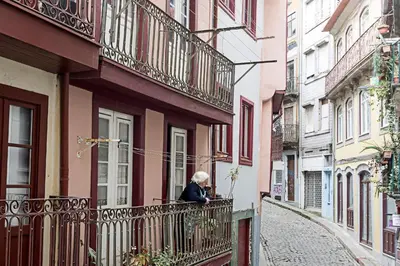 a woman standing on a balcony of a building at Lóios 1BR Flat Downtown by LovelyStay in Porto