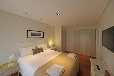 a bedroom with a large white bed and a television at FLH Sá da Bandeira Modern Apartment in Porto