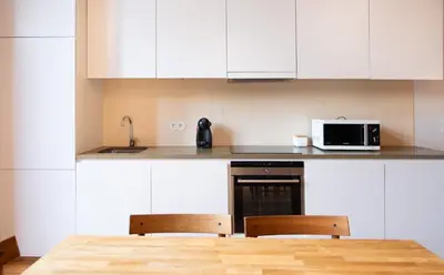 a kitchen with white cabinets and a table and two chairs at Batalha Garden Apartment in Porto
