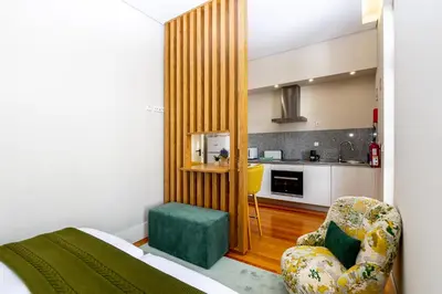 a bedroom with a bed and a chair and a kitchen at Mouzinho 129 - Medronheiro & Oliveira in Porto