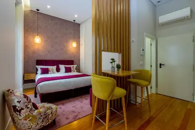 a hotel room with a bed and a table and chairs at Mouzinho 129 - Medronheiro & Oliveira in Porto