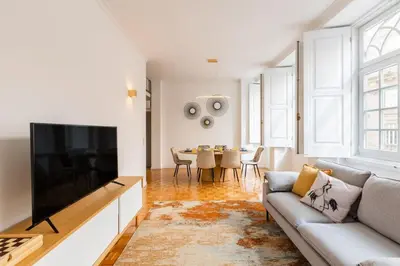 a dining room with a table and chairs and windows at São Bento Deluxe 42 with Balcony in Porto