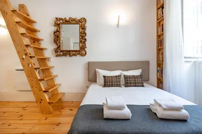 a bedroom with a bed with a ladder and a mirror at VIVA Library Studio in Porto