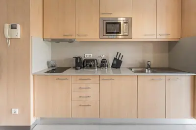 a kitchen with wooden cabinets and a sink and a microwave at GuestReady - Antas Studio in Porto