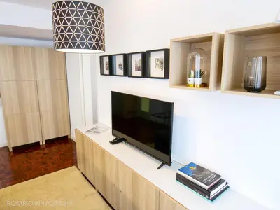 a living room with a flat screen tv on a wall at rosario inn porto in Porto