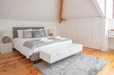 a white bedroom with a large bed and a rug at Tomas Loft in Porto