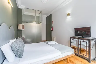 a bedroom with a bed and a flat screen tv at GuestReady - Gold Leaf in Porto