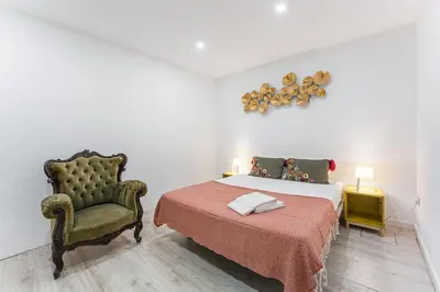 a bedroom with a bed and a chair at GuestReady - Gold Leaf in Porto