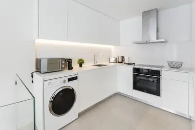 a white kitchen with a washing machine and a microwave at GuestReady - Porto by the Bridge in Vila Nova de Gaia