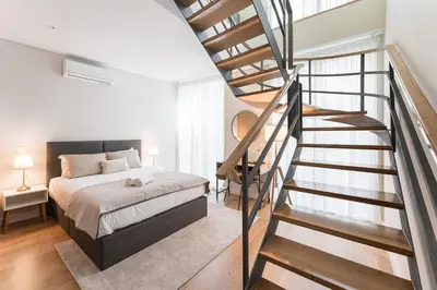 a bedroom with a bed and a spiral staircase at GuestReady - Porto by the Bridge in Vila Nova de Gaia