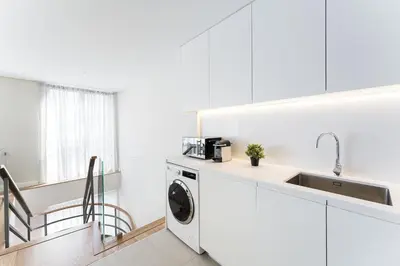 a white kitchen with a washing machine and a sink at GuestReady - Porto by the Bridge in Vila Nova de Gaia