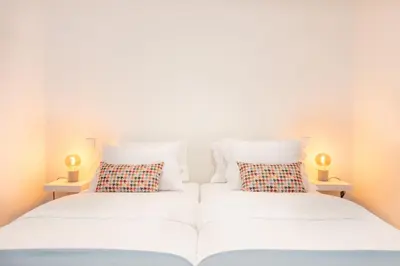 two beds in a room with two lamps on tables at 12 Sweet Caroline in Porto