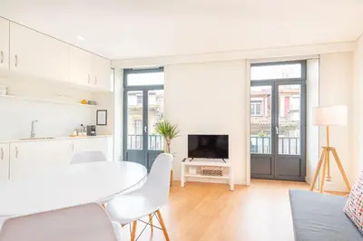 a white kitchen and living room with a white table and chairs at 12 Sweet Caroline in Porto