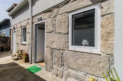 a stone house with a window and a green floor at Casa do Bonjardim, Lapa - Estadia no coração do Porto in Porto