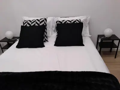 a black and white bed with black pillows on it at TMJ Apartamento in Porto