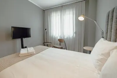 a bedroom with a large white bed and a lamp at River Eyes Suites in Vila Nova de Gaia