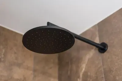 a black shower head hanging from a wall at GuestReady - Mercadores 150 in Porto