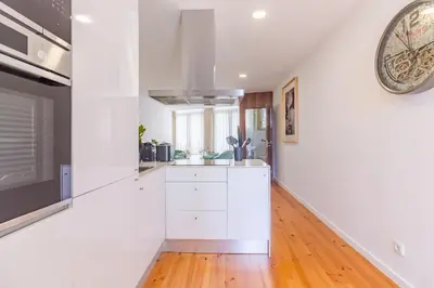a kitchen with white cabinets and a clock on the wall at OHH- Padre António Vieira flat D - 2bedroom near the train station in Porto