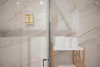 a bathroom with a shower with white marble walls at Cocoon Almada in Porto