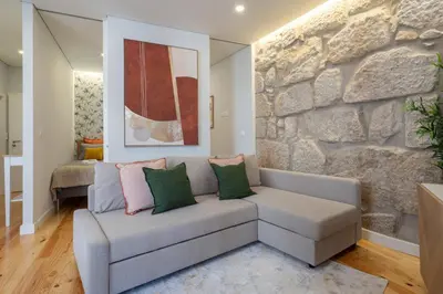 a living room with a couch and a stone wall at Host Wise - Enchanting Design Flat - Premium Location in Porto