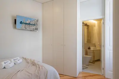 a white bedroom with a bed and a bathroom at Host Wise - Enchanting Design Flat - Premium Location in Porto
