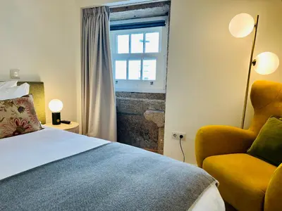 a bedroom with a bed and a chair and a window at CHARM APARTMENTS PORTO - Centro Batalha 1 in Porto