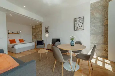 a living room with a table and chairs and a bedroom at Courtyard Oporto Design Apartments by Vacationy in Porto