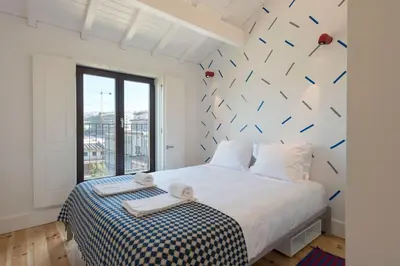 a bedroom with a large white bed with a black and white blanket at Boavista Penthouse w/ 2 Balconies & AC by LovelyStay in Porto
