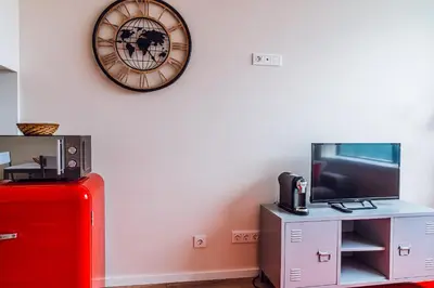 a room with a tv and a clock on the wall at Emotions Porto Flat in Porto