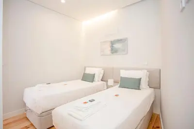 two beds in a small room with white walls at Liiiving in Porto - Aliados Stone Apartment in Porto