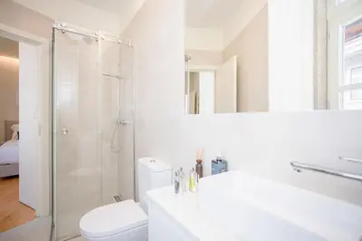 a white bathroom with a shower and a toilet at Liiiving in Porto - Aliados Stone Apartment in Porto