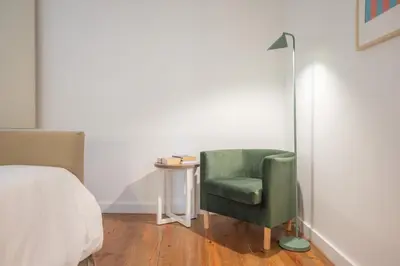 a bedroom with a green chair and a lamp at Fancy Ribeira Porto in Porto