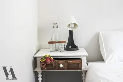 a bedside table with a lamp and glasses on it at Voga Apartments Sta Catarina in Porto