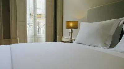 a bedroom with a white bed with a lamp and a window at Porto Republica Ribeira in Porto